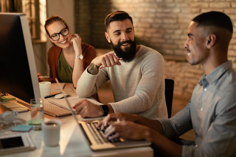 Group of happy colleagues talking while working in the office