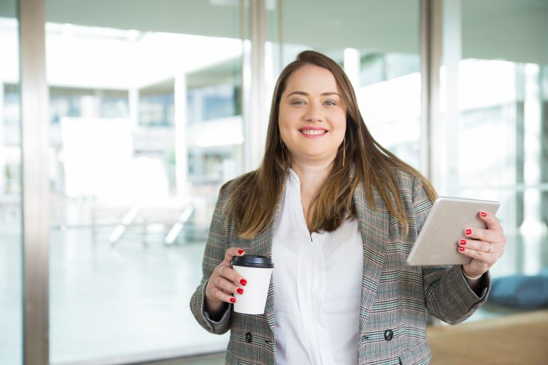 Happy business woman holding tablet and coffee outdoors