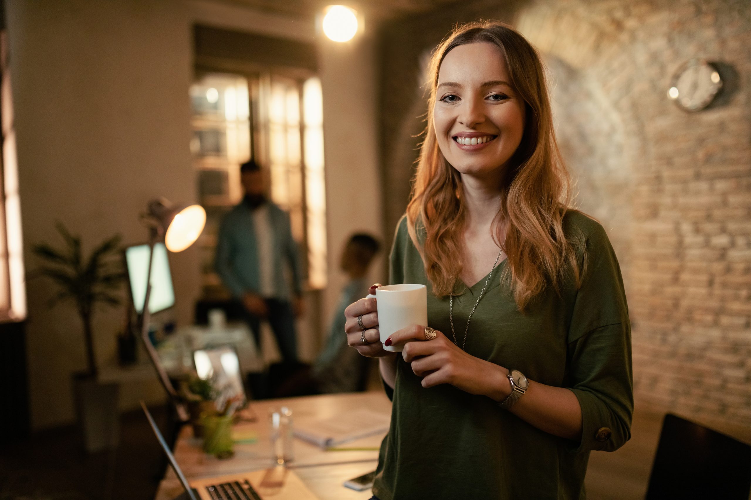 Portrait of happy businesswoman with coffee cup in the evening a